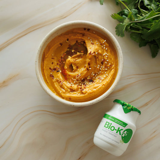 Hummus in a bowl with a Bio-K+ bottle