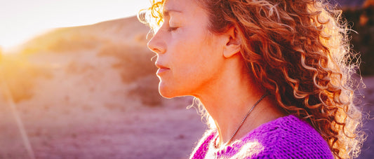 A woman breathing and relaxing with a rising sun.